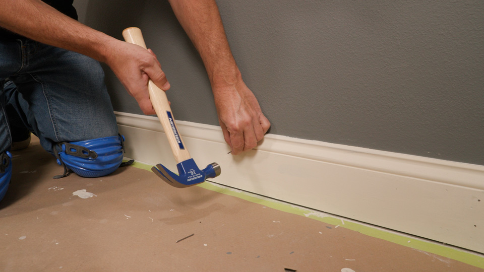 hammering a nail onto a baseboard